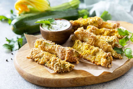 Healthy tasty snack, summer food. Zucchini fries. Crispy Zucchini sticks in breadcrumbs, with cheese with garlic yogurt sause.の写真素材