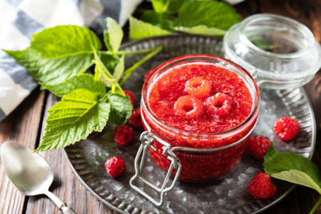 homemade preservation. Delicious raspberries jam or jelly on a rustic wooden table.