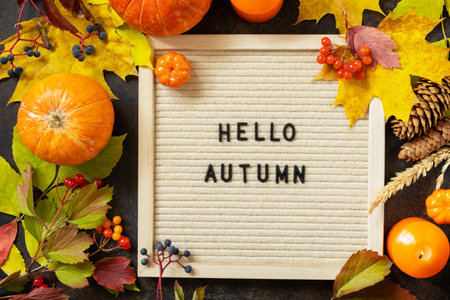 Autumn background with Hello Autumn letters and autumn message board, pumpkins and colorful leaves. Cozy autumn mood. Fall season greeting card.の写真素材