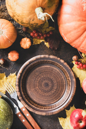 Thanksgiving day concept. Autumn table setting for dinner with plate, knife, fork decorated pumpkins and maple leaves. Flat lay autumn composition.の写真素材