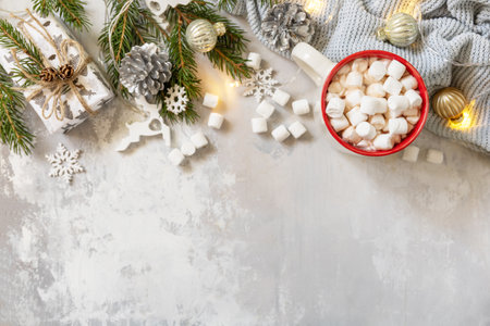 Christmas sweet drink concept. Christmas winter cozy cup hot chocolate drink with marshmallow and gifts, christmas lights, sweater knitted on a gray stone background. view from above. copyspace.の写真素材