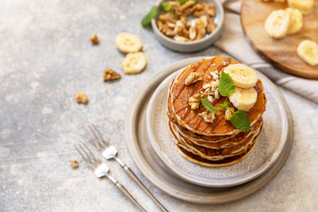 Celebrating Pancake day, american homemade breakfast. Banana gluten free pancakes with nuts and caramel on stone tabletop.の写真素材