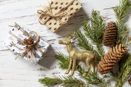 Christmas gold decor, christmas deer, fir tree twigs and gifts box on a white wood background. view from above.の写真素材