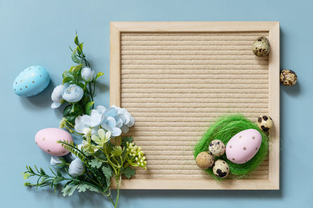 Springtime welcome concept. Letter board, Easter eggs and spring flowers on a pastel blue background, minimalism style composition. view from above.の写真素材