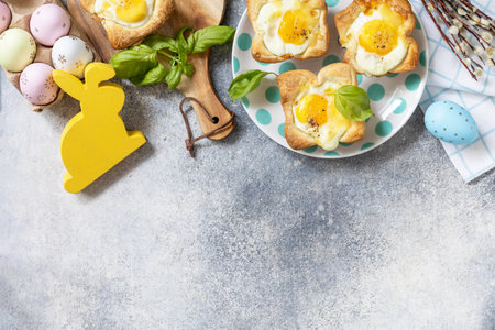 Easter breakfast idea. Scrambled eggs in puff pastry with cheese and bacon on a stone background. view from above. copyspace.の写真素材