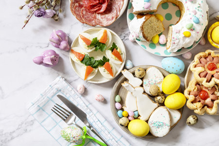 Festive dinner, Easter brunch. Easter table scene with an assortment of baking, desserts, stuffed eggs and dyed eggs on a marble background. view from above. copyspace.の写真素材