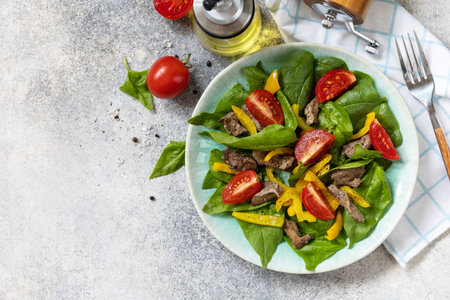 Warm salad of young spinach, chicken liver, tomatoes and grilled peppers with spices and balsamic. Healthy keto diet low carb. view from above. copyspace.の写真素材