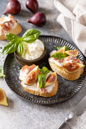 Toast or bruschetta with bacon and figs, cream cheese and honey on a gray stone background. Italian appetizer recipe. Copy space.の写真素材