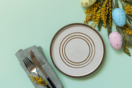 Table setting for Easter dinner with easter eggs and mimosa on a pastel background. Easter...
