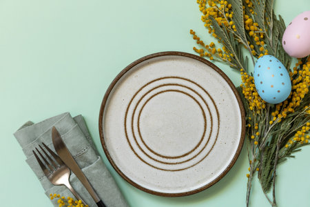 Table setting for Easter dinner with easter eggs and mimosa on a pastel background. Easter...
