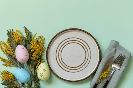 Table setting for Easter dinner with easter eggs and mimosa on a pastel background. Easter...