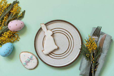 Table setting for Easter dinner with easter eggs and mimosa on a pastel background. Easter...