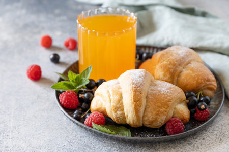 Tasty freshly baked croissants and orange juice on a gray stone background, breakfast concept. Dessert French pastry.の写真素材
