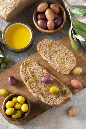 Mediterranean snack with mixed olives, olive oil, and rustic bread on wooden board.の写真素材