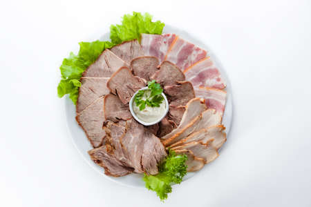 Different smoked ham and bacon with lettuce on white backgroundの写真素材