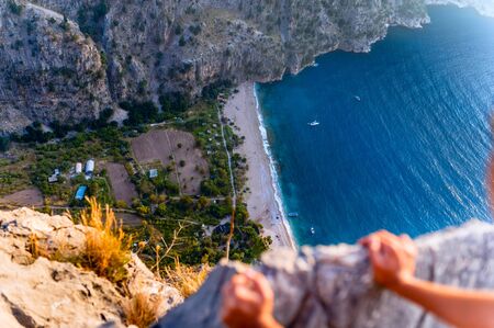 man looks down on the sea from a cliff. Valley of the Butterflies, Turkeyの写真素材