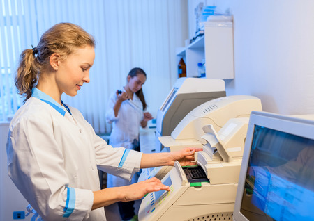 Woman doctor in a white bathrobe working with equipment in the modern laboratory