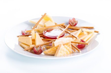 Cheese assorted with crackers, grapes and jam on a white backgroundの写真素材