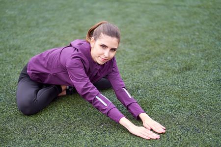 Young sporty woman stretching on a football field.の写真素材