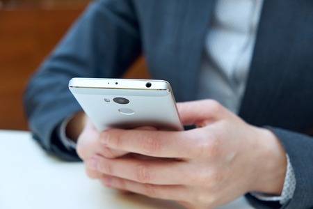 Woman business holding smart phone with blurred background.