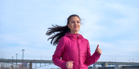 Running athlete woman sprinting during winter training outside in cold snow weather. Close up...