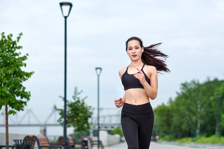 Beautiful woman running over bridge during sunset.の写真素材