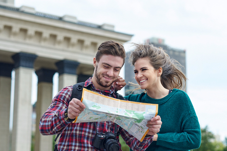 Young couple with a map in the city. Happy tourists sightseeing city with map.の写真素材