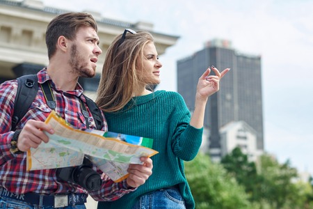 Young couple with a map in the city. Happy tourists sightseeing city with map.の写真素材