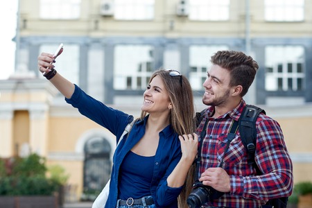 Happy couple of tourists taking selfie in showplace of city.の写真素材