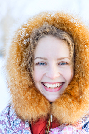 beautiful Russian woman in a fur hood and woolen mittens. Outdoor fashionable winter portraitの写真素材