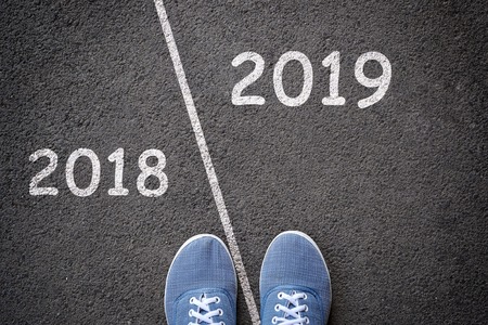 Start new year 2019 and leaving behind old year. Feet in blue jeans sneakers standing on different sides of the line. Concept for success and passing timeの写真素材