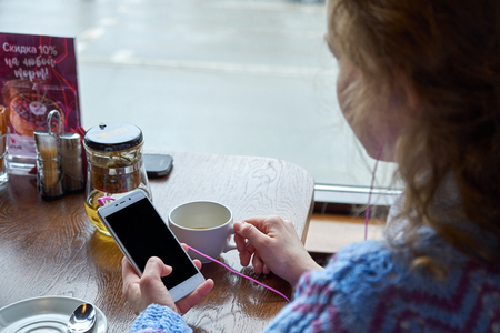 woman using smartphone in coffee shop in cafe with cup of coffeeの写真素材