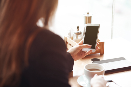 Woman hands with smart phone, headphones and cup of tea. For Graphic display montageの写真素材