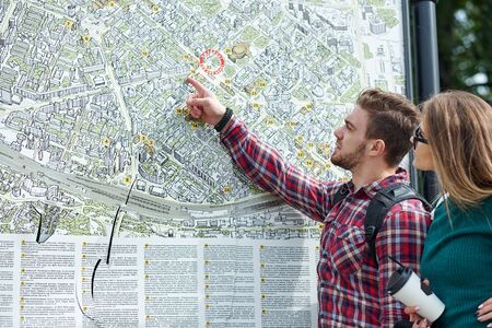 Young couple with a map in the city. Happy tourists sightseeing city with map.の写真素材
