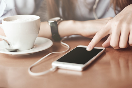 Woman hands with smart phone, headphones and cup of tea. For Graphic display montage