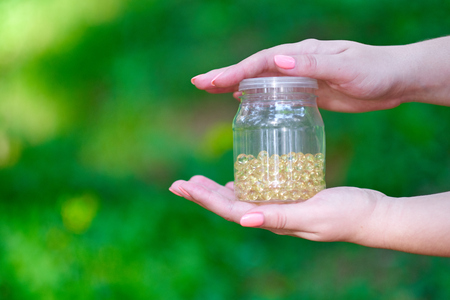 hand holding daily supplements, vitamins or medication on green backgroundの写真素材