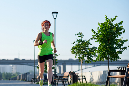 Beautiful woman running over bridge during sunset.の写真素材