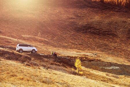 car and two people at sunset in the mountains. Altai, Russiaの写真素材