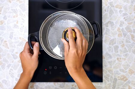 Women hand open a saucepan in modern kitchen with induction stoveの写真素材