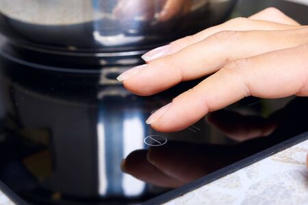 Woman hand includes modern induction stove