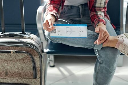 Hand holding tickets or boarding pass. Air travel at gate waiting in terminalの写真素材