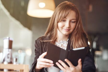 Young woman in a cafe reading an ebook and drinking coffee.