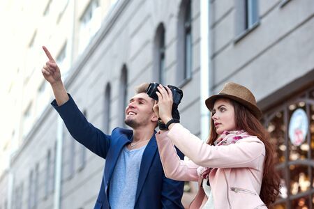 Happy love couple of tourists taking pointing to a landmark or showplace in the city