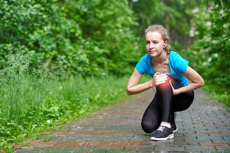 Woman athlete runner touching Knee in pain, fitness woman running in summer park. Healthy lifestyle...