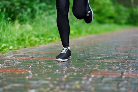 Legs of Running woman atletic spotsman trains in the summer park. Outdoor fitness portrait after rainの写真素材