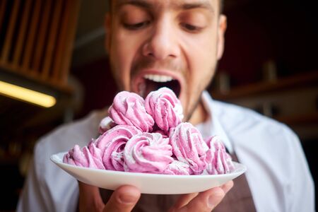 Funny man cook tasting dessert. Brutal confectioner hungry