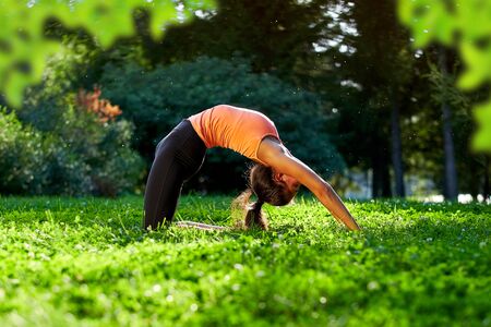 Yoga. Young woman practicing yoga or dancing or stretching in nature at park. Health lifestyle concept.の写真素材