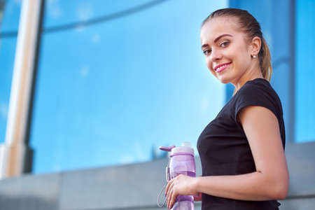 Fitness woman drinking water after running training in workout sports ground