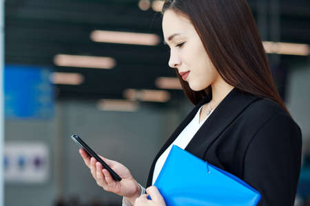 Asian Business woman using mobile phone. Portrait of beautiful girl in office or meeting room.の写真素材