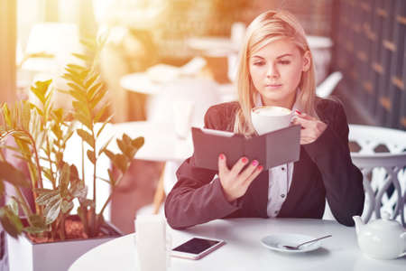 Young woman in cafe reading an ebook and drinking coffeeの写真素材